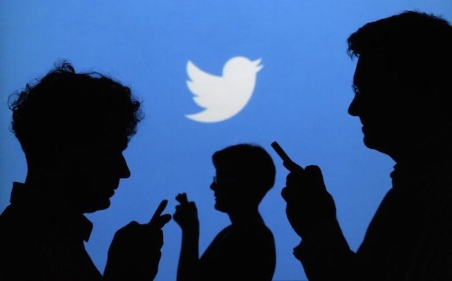 People holding mobile phones are silhouetted against a backdrop projected with the Twitter logo in this illustration picture taken in  Warsaw September 27, 2013. REUTERS/Kacper Pempel
