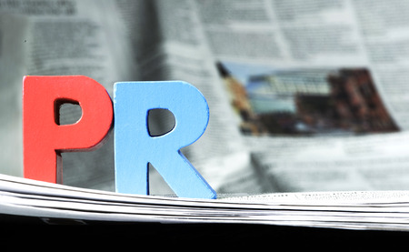 27214281 - word pr on newspaper. wooden letters